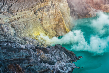 Active volcano with sulphur smoke floating and turquoise lake at Kawah Ijen