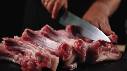 The chef cuts raw meat with a knife in slow motion. Raw beef steak sliced on a wooden board. Delicious food concept