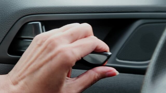 Close-up of a woman's hand opening a car door from the inside.