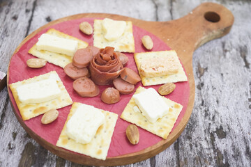 Cheese, Crackers, Sausage, and Almond nuts platter. Cheese plater on wooden plate for breakfast and snacking.