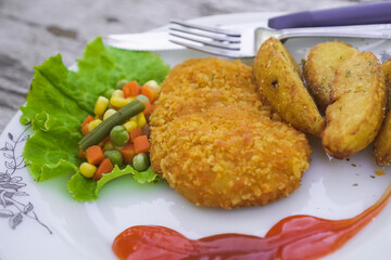 Steak on a ceramic plate on a wooden table. Fried chicken steak served with tomato sauce and mixed vegetables. Concept for healthy food, fat loss, weight loss.