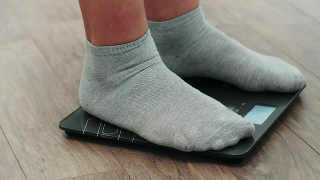Fat man in socks on the weight scales. A man is weighed for weight control.