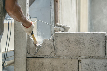 Hand of worker using hammer smashing and demolish on brick wall at construction site