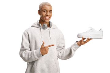 Cool african american guy holding a white sneakers and pointing
