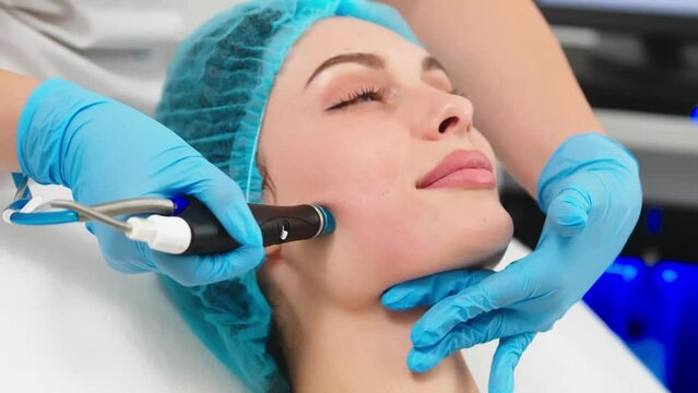 Beauty therapist performing hydrafacial procedure on woman