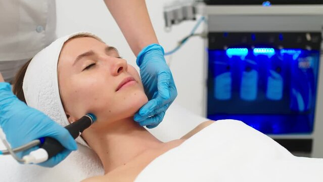 Beauty therapist performing hydrafacial procedure on woman