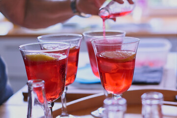filling of glasses with red aperitif with lemon zest