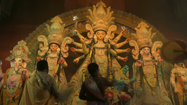 Howrah, West Bengal, India - 3rd October, 2022 : Hindu Priests worshipping Goddess Durga with white conch shell. Ashtami puja aarati - sacred Durga Puja ritual - fetival of Hinduism, at night.