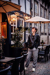 Young woman in black leather jacket with short dark hair standing in german city
