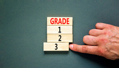 Time to grade 3 symbol. Concept word Grade 1 2 3 on wooden block. Businessman hand. Beautiful grey table grey background. Business planning and time to grade 3 concept. Copy space.