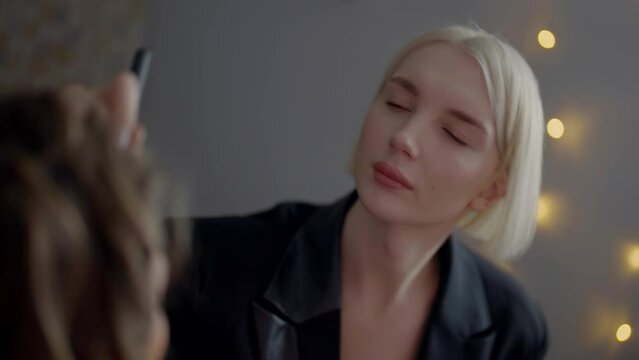 portrait of androgynous person with blonde hair, makeup artist during work in beauty salon, lgbt
