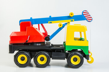 Multi-colored plastic toy trucks for children's games on a white background. Truck crane.