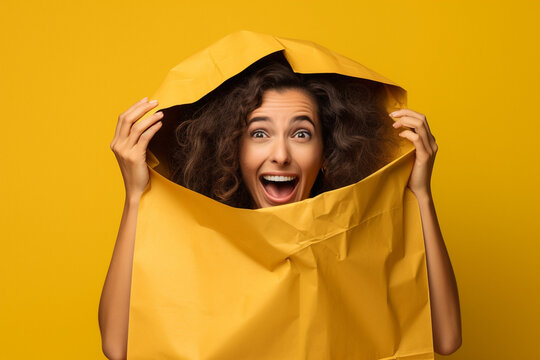 Young funny woman hiding under the yellow bags isolated on yellow background. Shopping, sales concept. High quality photo