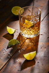 Summer drink, whiskey, tequila or cognac, lemonade, alcoholic or non-alcoholic cocktail with limes and salt on a wooden table