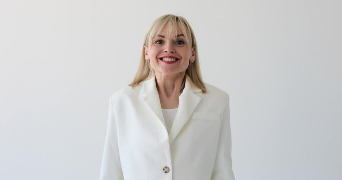 Friendly blonde woman dressed in a professional suit is seen on a white backdrop, expressing a surprised and delighted expression. Her warm and approachable demeanor adds to the sense of friendliness.