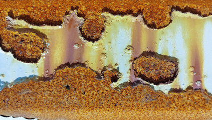 A fragment of the surface of an oil tank that has lost its protective white epoxy-polyurethane coating and is very heavily corroded.