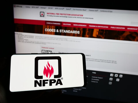 Stuttgart, Germany - 07-13-2023: Person holding cellphone with logo of National Fire Protection Association (NFPA) on screen in front of webpage. Focus on phone display.