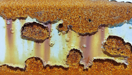 A fragment of the surface of an oil tank that has lost its protective white epoxy-polyurethane coating and is very heavily corroded.