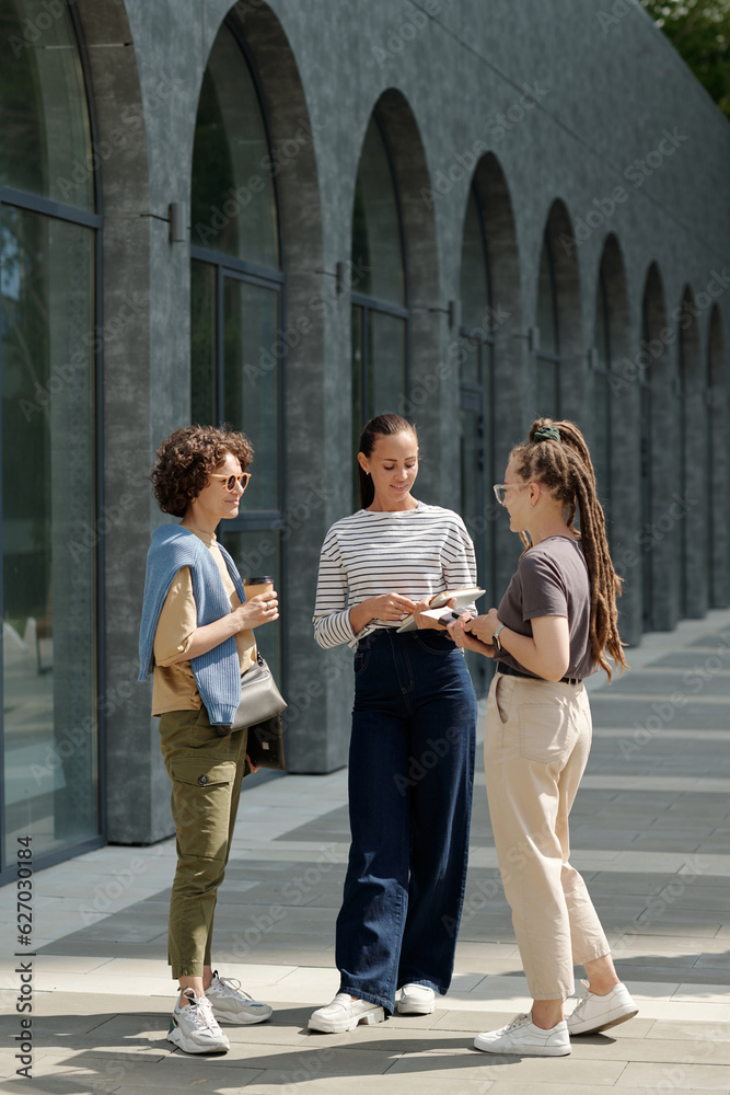 Aufkleber three young businesswomen in casualwear standing in front of camera and having discussion of working