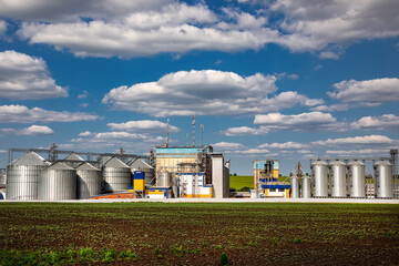 Agricultural Silos. Storage and drying of grains, wheat, corn, soy, sunflower against the blue sky with white clouds.Storage of the crop.