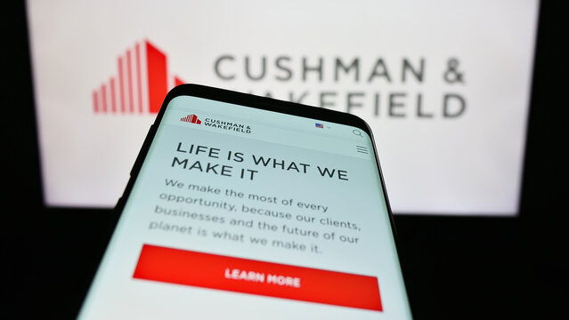 Stuttgart, Germany - 07-15-2023: Mobile phone with website of real estate company Cushman Wakefield plc on screen in front of business logo. Focus on top-left of phone display.