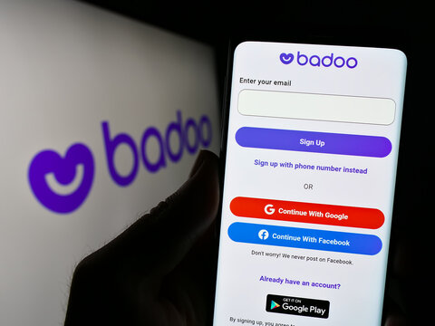 Stuttgart, Germany - 07-15-2023: Person holding cellphone with website of dating platform Badoo (Bumble Inc.) on screen in front of logo. Focus on center of phone display.
