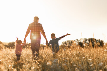 Father and his children walking in a field at sunset enjoying time together in nature 