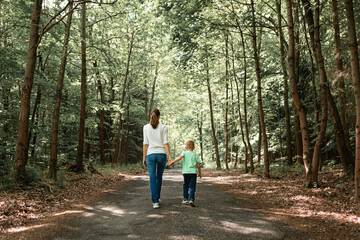 Mother and child walking in the forest holding hands enjoying a walk in nature 