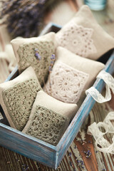 Sachet bags decorated with crocheted lace and lavender on a wooden background