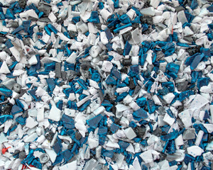 Recycled crushed plastic. Recycling and reuse of plastic. The problem of environmental pollution. Ecology and innovations. Various types of plastic in white and blue color.