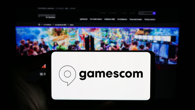 Stuttgart, Germany - 07-15-2023: Person holding mobile phone with logo of German video game trade fair gamescom (Cologne) on screen in front of web page. Focus on phone display.