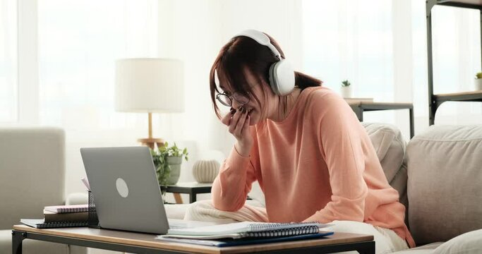 In a state of amazement, a teenage girl wearing headphones utilizes her laptop for video communication. Her eyes widen with surprise and intrigue as she engages in the virtual conversation.