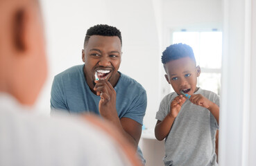 Black man brushing his teeth with his kid for dental hygiene, health and wellness in the bathroom. Oral care, teaching and young African father doing morning mouth routine with his boy child at home.