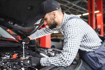 Fototapeta na wymiar Mechanic examining under hood of car at the repair garage