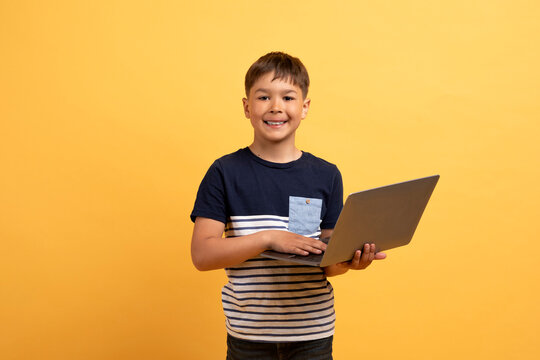 Cool preteen cute boy holding laptop computer and smiling