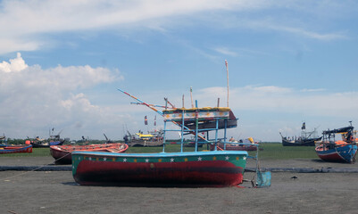 Fototapeta premium Fishing boats are waiting for the tide.So the fishermen are repairing the nets sitting in boat.Fishermen will go to the sea and catch the popular fish Hilsa.