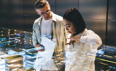 Focused diverse colleagues standing in building models counter