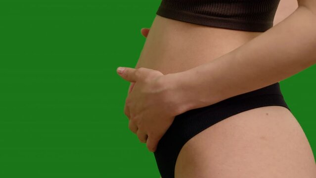 Front and side view of early pregnant woman obsessed with her growing stomach on green screen background. Healthcare during pregnancy, female making energetic connection with her fetus.