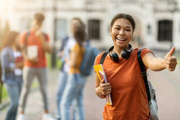 Study Abroad. Happy Black Female Student Posing Outdoors And Showing Thumb Up