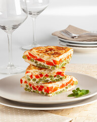 Red pepper, onion and asparagus omelette on a white plate.