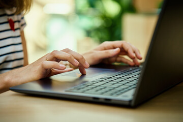 Hands typing on laptop keyboard. Close up shot of woman using laptop in cafe
