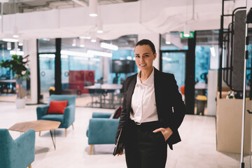 Fototapeta na wymiar Smiling businesswoman in formal suit standing in modern office
