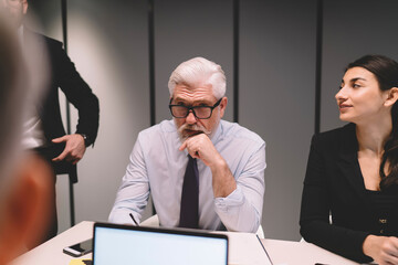 Serious senior man in glasses speaking during meeting