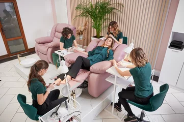 Outdoor kussens Woman relaxing in comfortable salon chair while having manicure, pedicure and eyelash extension procedure. Manicurist, pedicurist and eyelash specialist working with client in modern beauty salon. © anatoliy_gleb