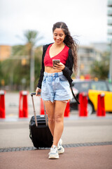 Full body young travel woman walking with suitcase and mobile phone