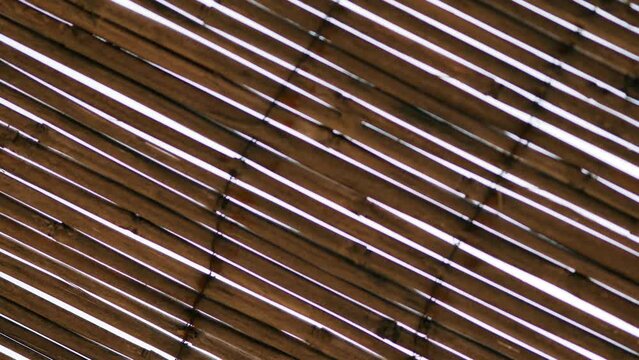 Reed canopy in hot summer. Sky shines through cracks in bamboo or thatch roof above cafe near sea beach. Wooden natural ecologic plant material. Exotic travel. Rovinj, Croatia - July 23, 2023