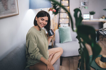 Obraz premium Smiling woman drinking coffee in living room