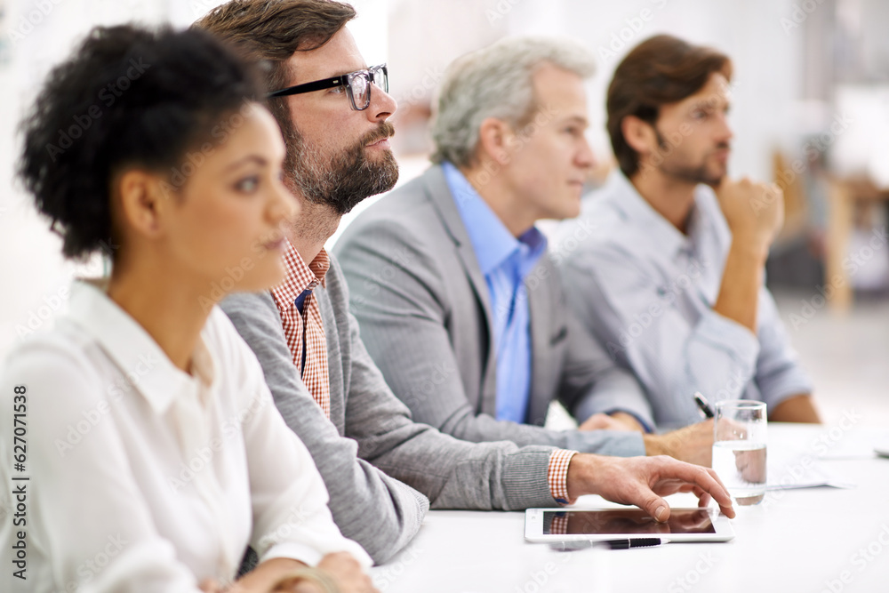 Poster project debriefing. shot of a group of dedicated business professionals sitting in a row.