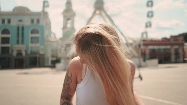 a beautiful girl in a white T-shirt poses in Kyiv against the backdrop of a Ferris wheel in the city center in summer