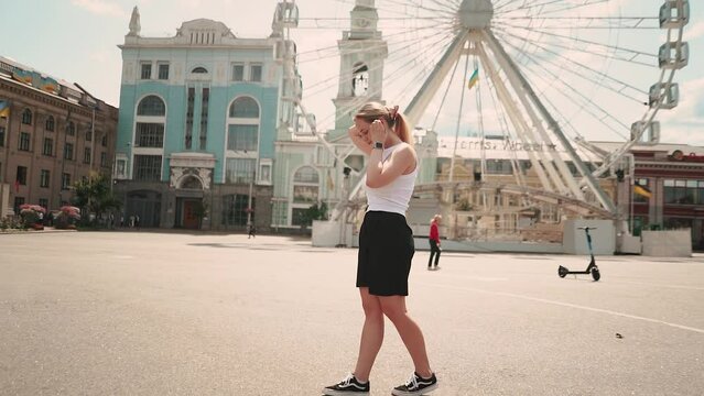 a beautiful girl in a white T-shirt poses in Kyiv against the backdrop of a Ferris wheel in the city center in summer